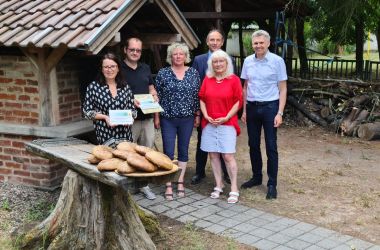 Eine Gruppe von Personen steht vor einem gemäuerten Holzbackofen.