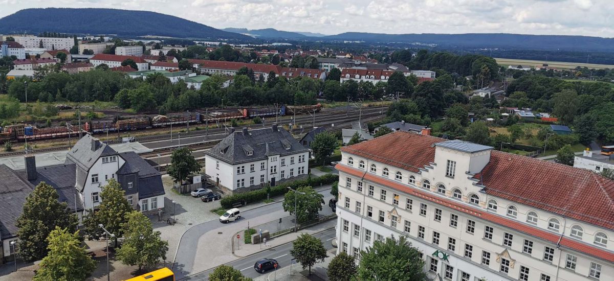 Drohnenaufnahme mit Blick auf den Bahnhof, das Rathaus und das AOK-Gebäude. Im Hintergrund ist der Stadtteil Wolkenrasen zu sehen.