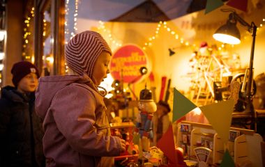 Kinder schauen in ein weihnachtlich geschmücktes Schaufenster.