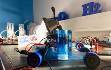 Ein Experimentierauto, welches mit Wasserstoff angetrieben wird, steht auf einem Tisch.