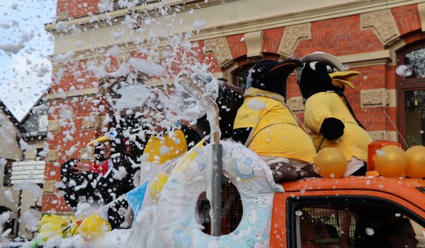 Schaum regnet von einem Fahrzeug des Faschingsumzugs.