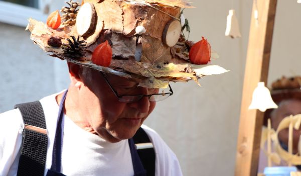 Ein Mann trägt einen Hut, der mit Blättern und Zapfen geschmückt ist.
