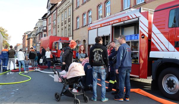Zwei Feuerwehrautos stehen in der Innenstadt. Davor stehen Interessierte.