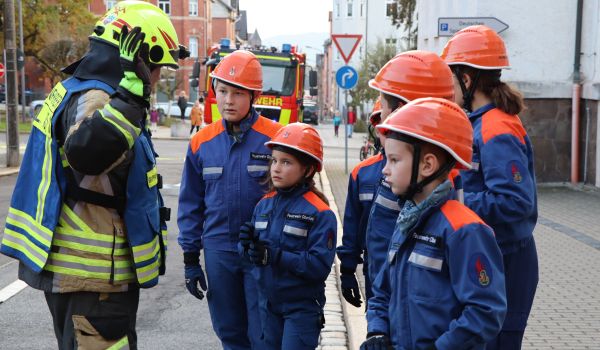 Kinder in Feuerwehruniform erhalten Anweisungen von einem Erwachsenen.