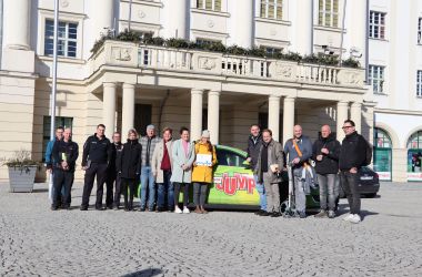 Mehrere Personen stehen auf dem Platz vor dem Rathaus der Stadt Sonneberg. Hinter ihnen steht ein Auto mit der Aufschrift: mdr Jump.