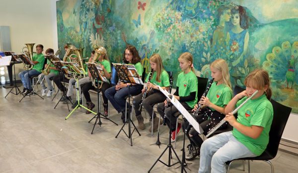 Kinder sitzen in einer Reihe und spielen Blasinstrumente.