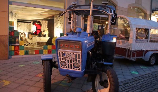 Ein Traktor mit überdachtem Anhänger steht vor der Weihnachtsmannwerkstatt in der Sonneberger Innenstadt.
