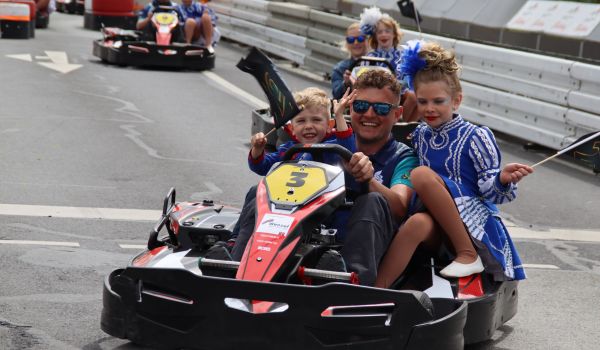Menschen fahren in Kartautos über eine Rennstrecke.