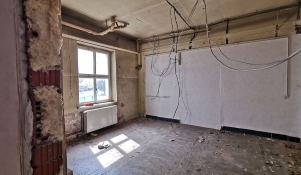 Eine Baustelle in einem Gebäude. Kabel hängen von der Decke.