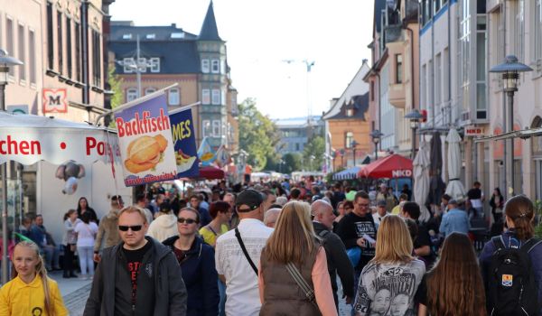Viele Menschen laufen durch die Innenstadt. Links und rechts stehen Verkaufstände.