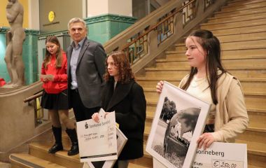 Drei Schülerinnen stehen mit einem Mann auf einer Treppe im Foyer des Sonneberger Rathauses.