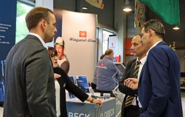 Menschen stehen vor einem Messestand und unterhalten sich.