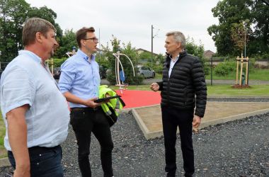 Drei Männer stehen auf einer Baustelle und sprechen miteinander.