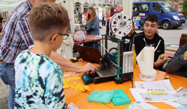 Kinder schauen sich einen 3D-Drucker an.