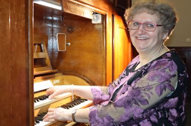 Eine Frau sitzt an einer Orgel und spielt.