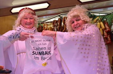 Zwei Frauen im Christkind-Kostüm halten einen Beutel hoch.