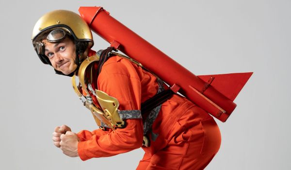 Ein Mann trägt rote Kleidung, einen goldenen Helm und hat eine rote Rakete auf seinem Rücken.