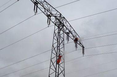 Nahaufnahme: Ein Person klettert auf einen Hochspannungsmasten.