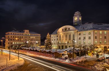 Das Sonneberger Rathaus mit Turm. Davor stehen die Holzhütten des Weihnachtsmarktes und in der Mitte ein großer Weihnachtsbaum. Es ist dunkel und es liegt Schnee.