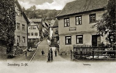Ein Schwarz-Weiß-Foto zeigt eine Straße mit Häuser. Darunter steht Sonneberg Gaisberg.