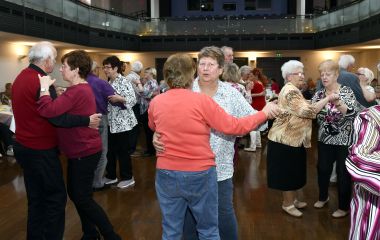 Senioren tanzen in einem großen Saal.