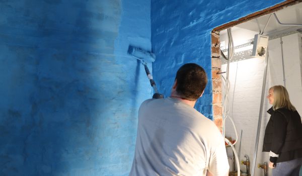 Ein Mann streicht eine Wand blau.