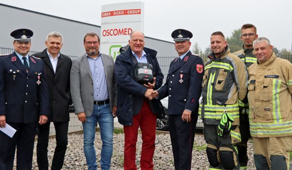 Feuerwehrmänner stehen vor einer Firma und nehmen eine Spende in Empfang.