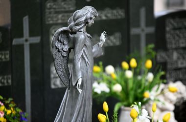 Eine scharze Engelsfigur auf einem Friedhof.