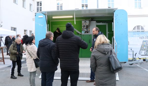 Interessierte Gäste schauen sich eine technische Anlage in einem Container an.