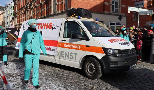 Personen laufen neben einem Rettungswagen. Sie sind als Chirurgen gekleidet.