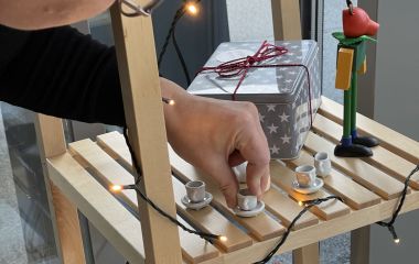 Ein Frau stellt eine Mini-Tasse in ein Regal.