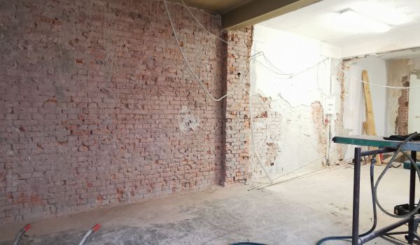 Eine Baustelle in einem Gebäude. Kabel hängen von der Decke.