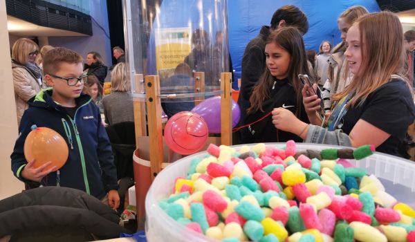 Kinder lassen Luftballons über eine Glasröhre aufsteigen.