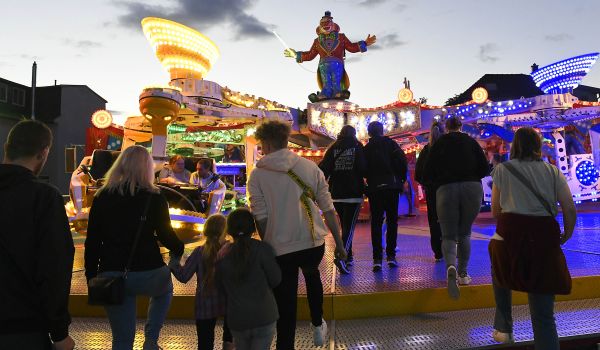 Beleuchtete Fahrgeschäfte und Verkaufsstände am Abend.