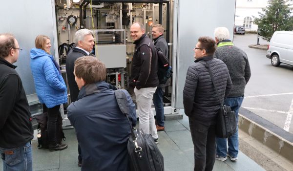 Interessierte Gäste schauen sich eine technische Anlage in einem Container an.