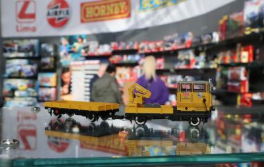 Ein gelbes Modellschienenfahrzeug steht auf einer Glasplatte.