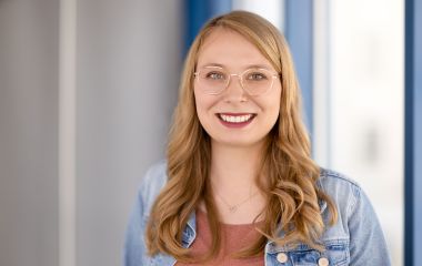 Eine Frau steht vor einem Fenster. Es ist Vivien Engel aus dem Sekretariat des Bauamtes.