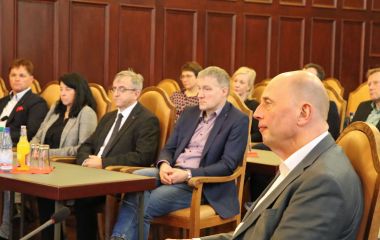 Mehrere Personen sitzen in Stuhlreihen nebeneinander.