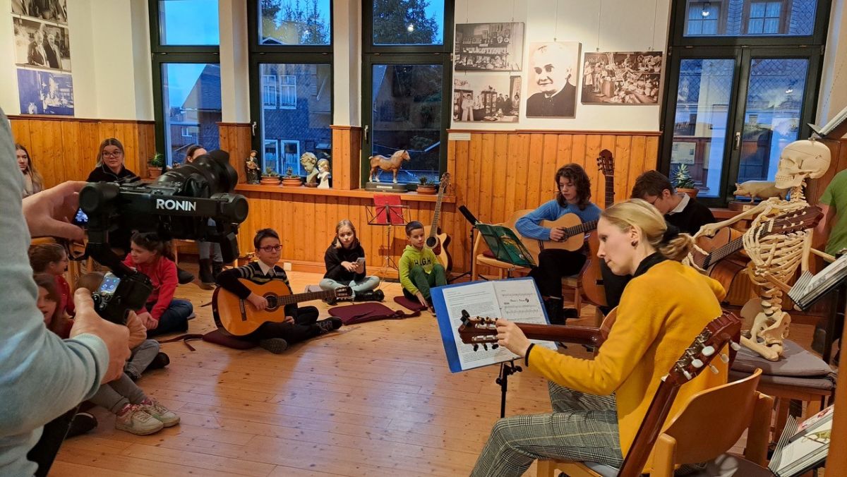 Kinder und Erwachsene sitzen im Kreis und musizieren.