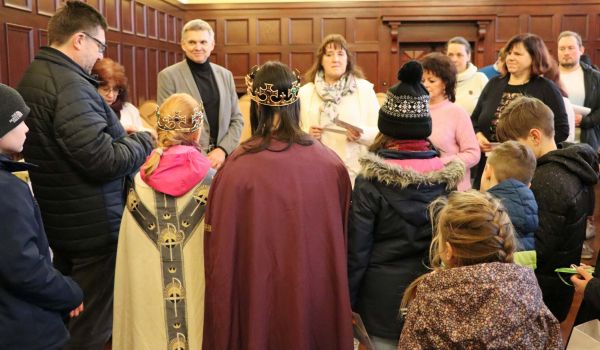 Die Sternsinger sind umgeben von weiteren Kindern und Erwachsenen.