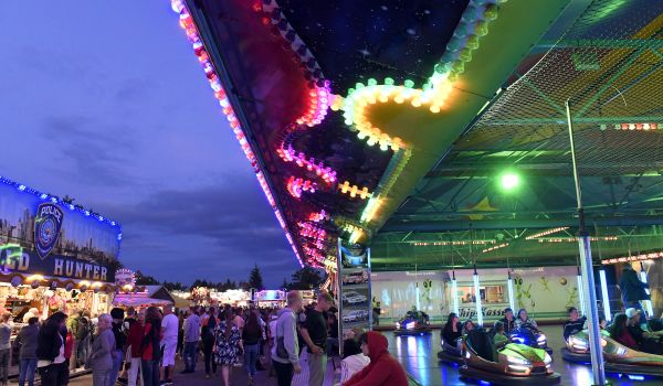 Beleuchtete Fahrgeschäfte und Verkaufsstände bei Nacht.