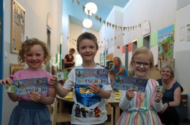 Drei Kinder halten einen Gutschein für das SonneBad und eine Freikarte für den Tiergarten Sonneberg in der Hand. Sie lächeln.