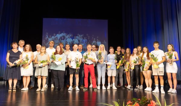 Jugendliche und Erwachsene stehen mit Präsenten auf einer Bühne.