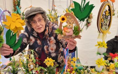 Ein Frau hinter einer Verkaufstheke zeigt ihre bunte Osterdeko.