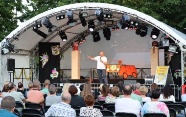 Ein Mann steht auf einer Bühne und spricht in ein Mikrofon.