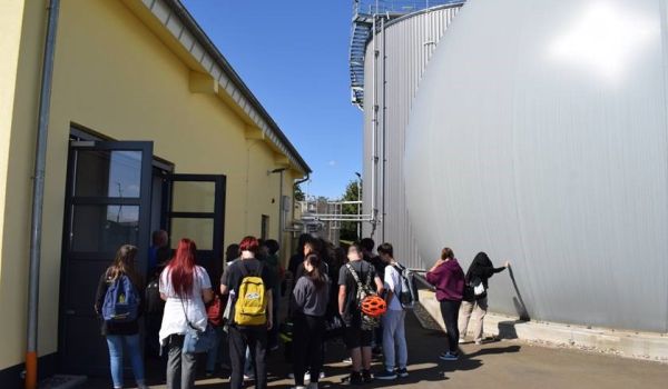 Jugendliche stehen vor einer Kläranlage.