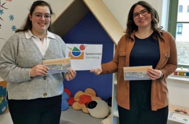Zwei Frauen stehen nebeneinander und halten einen Zettel mit der Aufschrift Spatzennest Sonneberg in der einen Hand und einen Gutschein fürs Sonnebad in der anderen Hand.