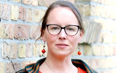 Eine Frau vor einer Steinmauer.