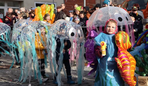 Kinder tragen Regenschirme, die als Quallen geschmückt sind.