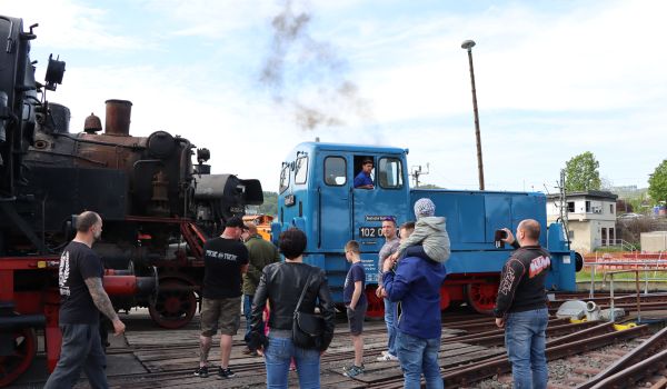 Menschen stehen vor einer alten blauen Lok.